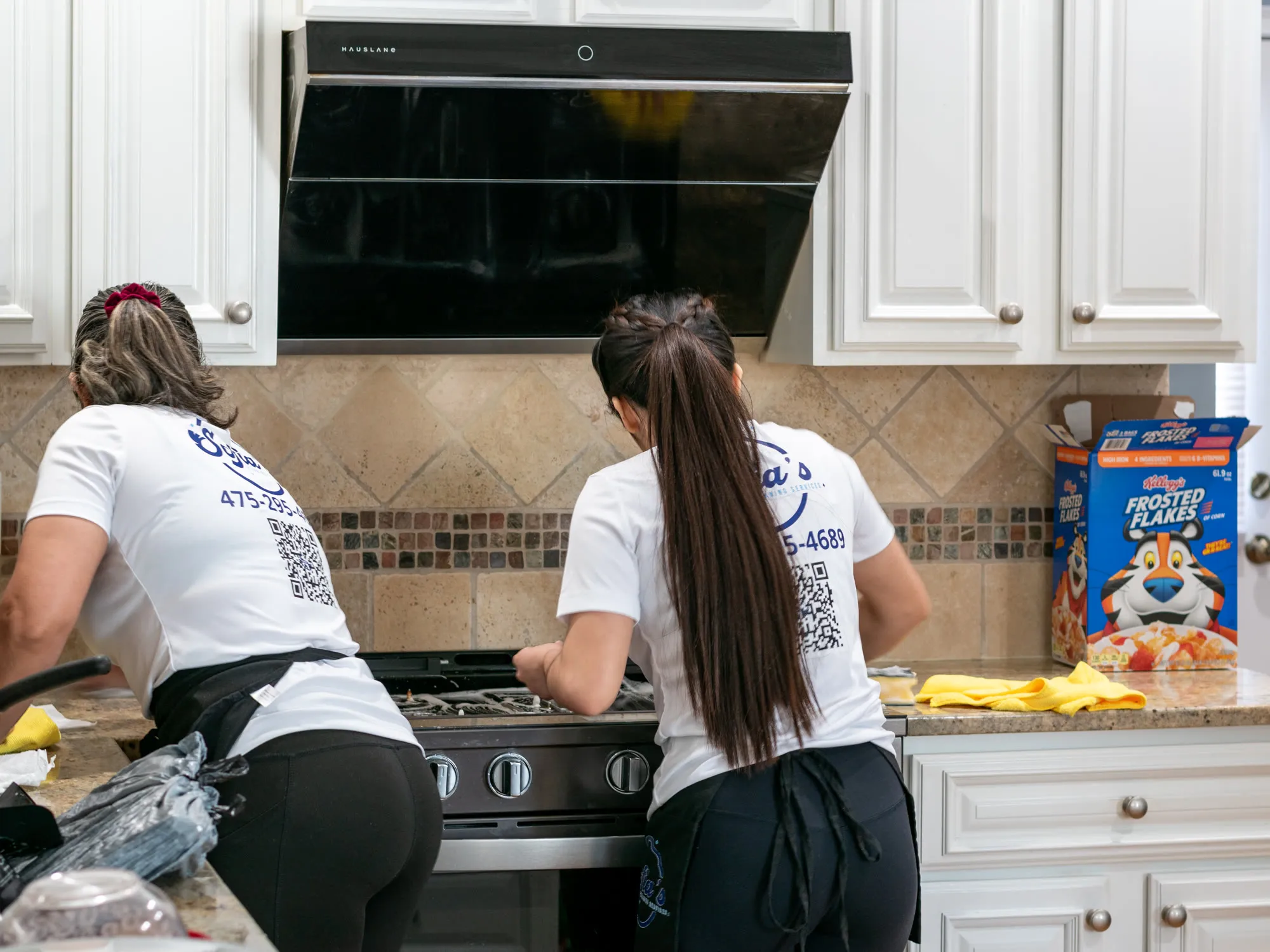 Two Sofia’s cleaners detailing a kitchen range and backsplash