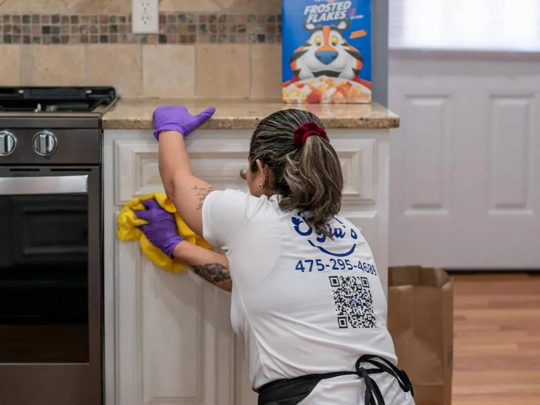 A Sofia’s cleaner wiping down kitchen cabinet doors