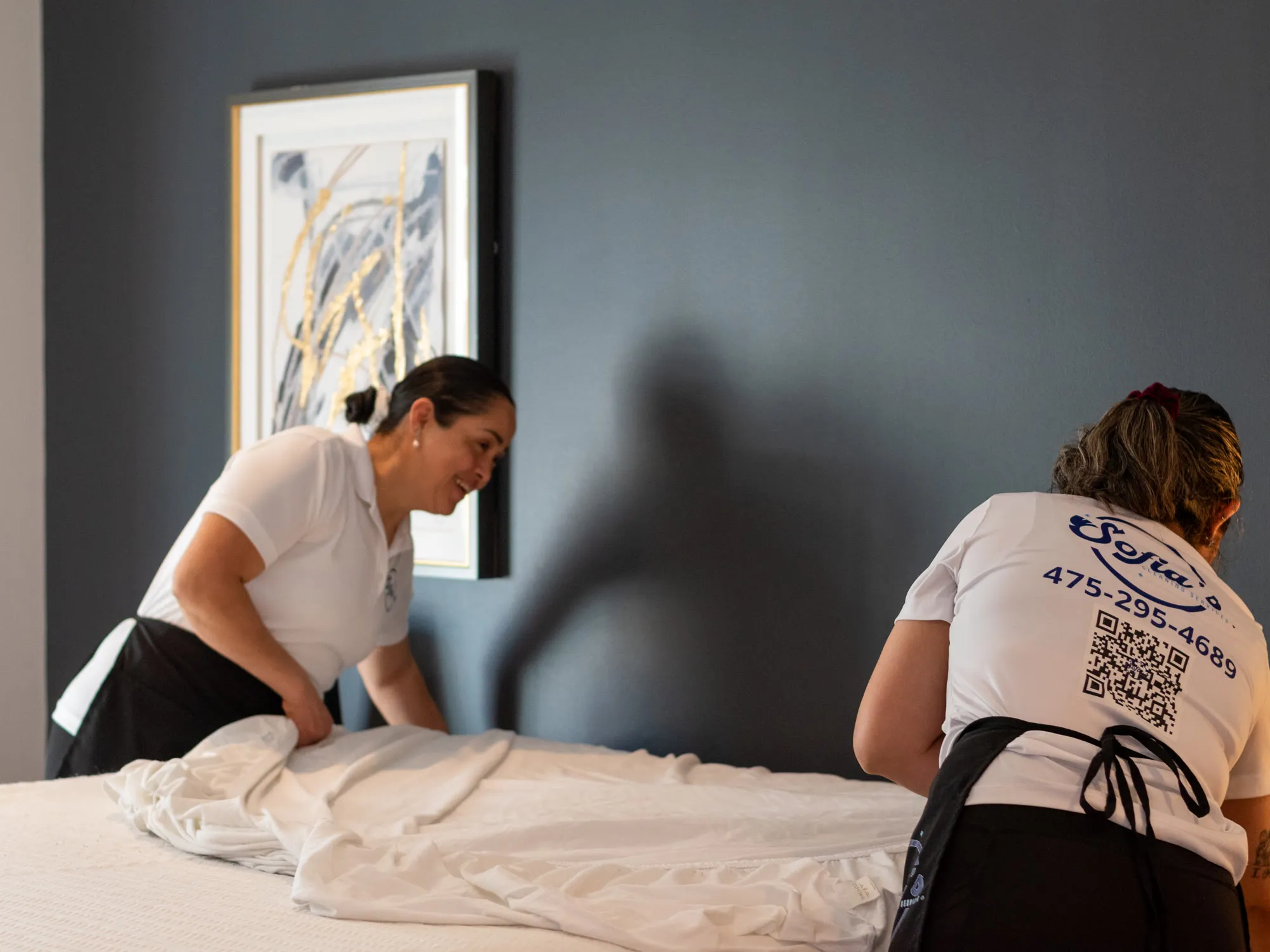 Two Sofia’s cleaners making a bed with fresh white linens